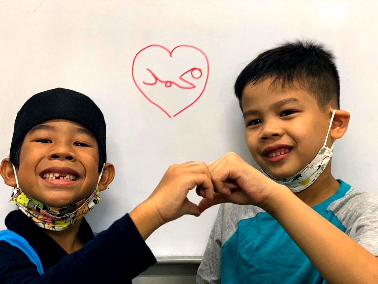 Dua murid Al-Wardah tersenyum membuat bentuk hati